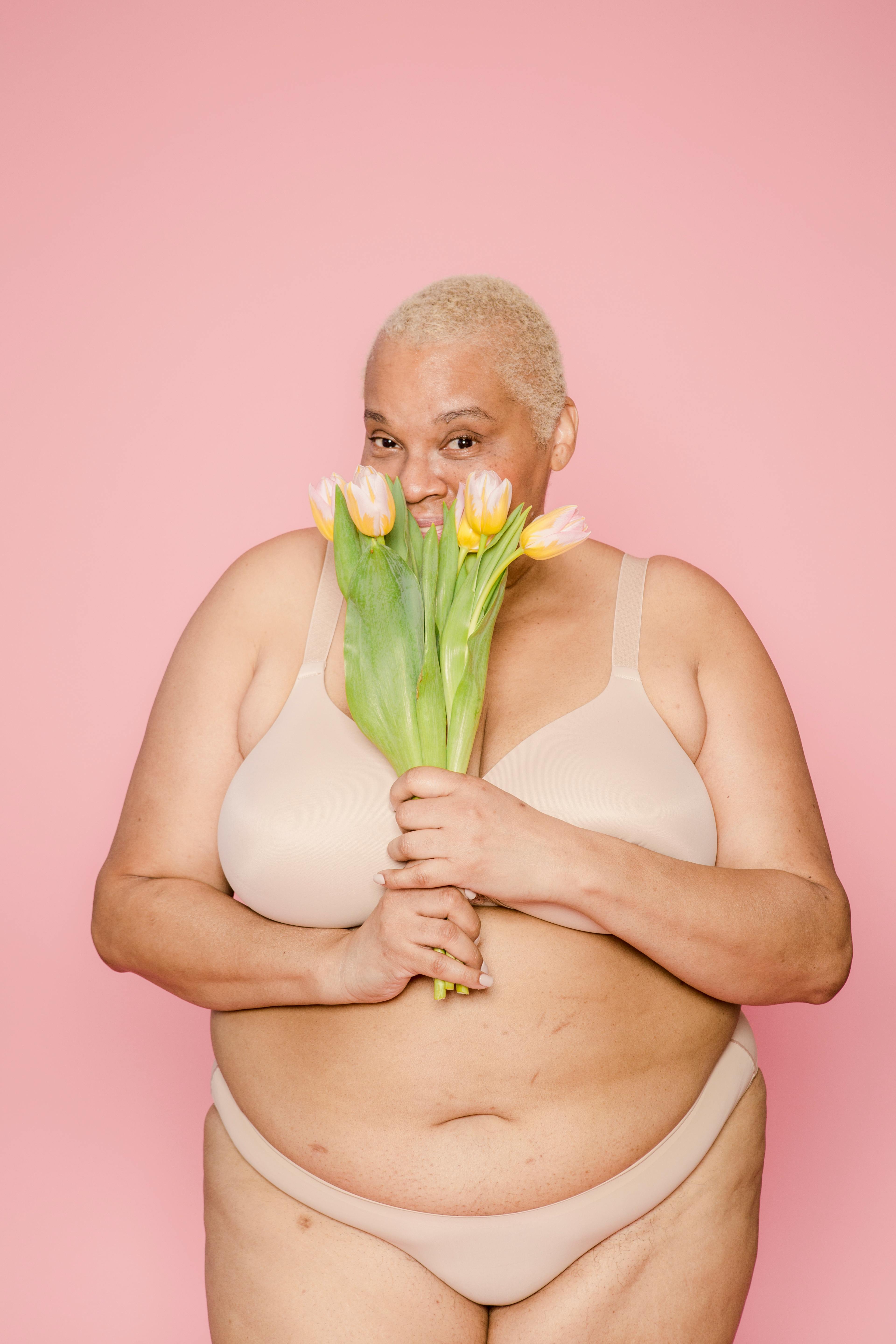 Black overweight woman in tight underwear sitting in studio · Free