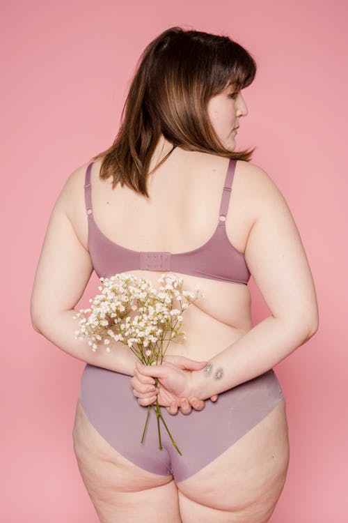 Anonymous overweight woman in underwear with bouquet