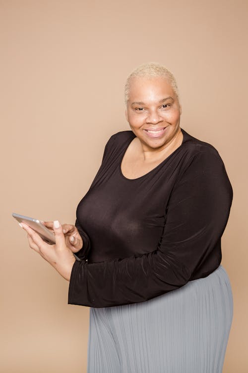 Positive plump black woman browsing tablet