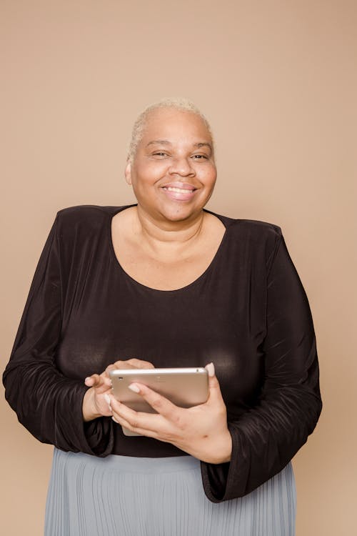 Joyful overweight black woman using tablet