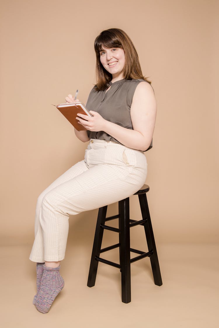 Cheerful Overweight Asian Woman Writing In Notebook