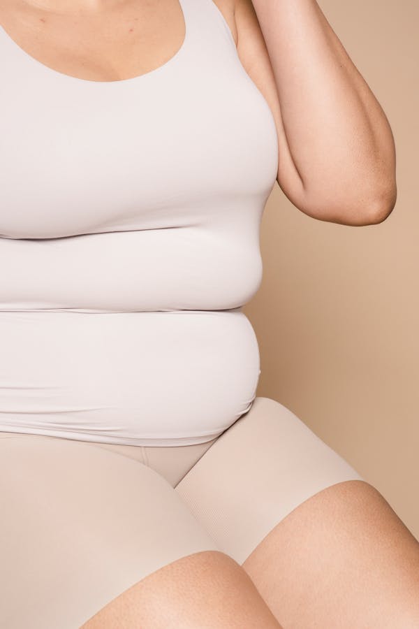 Faceless overweight woman in light clothes
