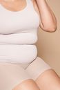 Faceless overweight woman in light clothes