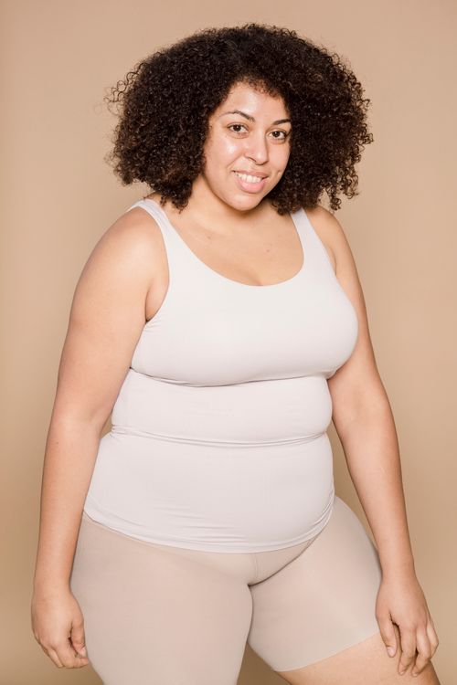 Free Delighted plump African American female with black hair wearing shorts smiling and looking at camera on beige background in studio Stock Photo