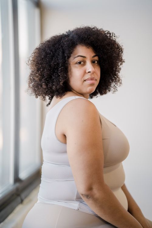 Free Side view of adult plus size African American female in underclothes with curly hair looking at camera Stock Photo