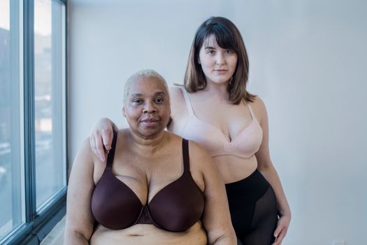 Plump multiethnic models in underwear on light background