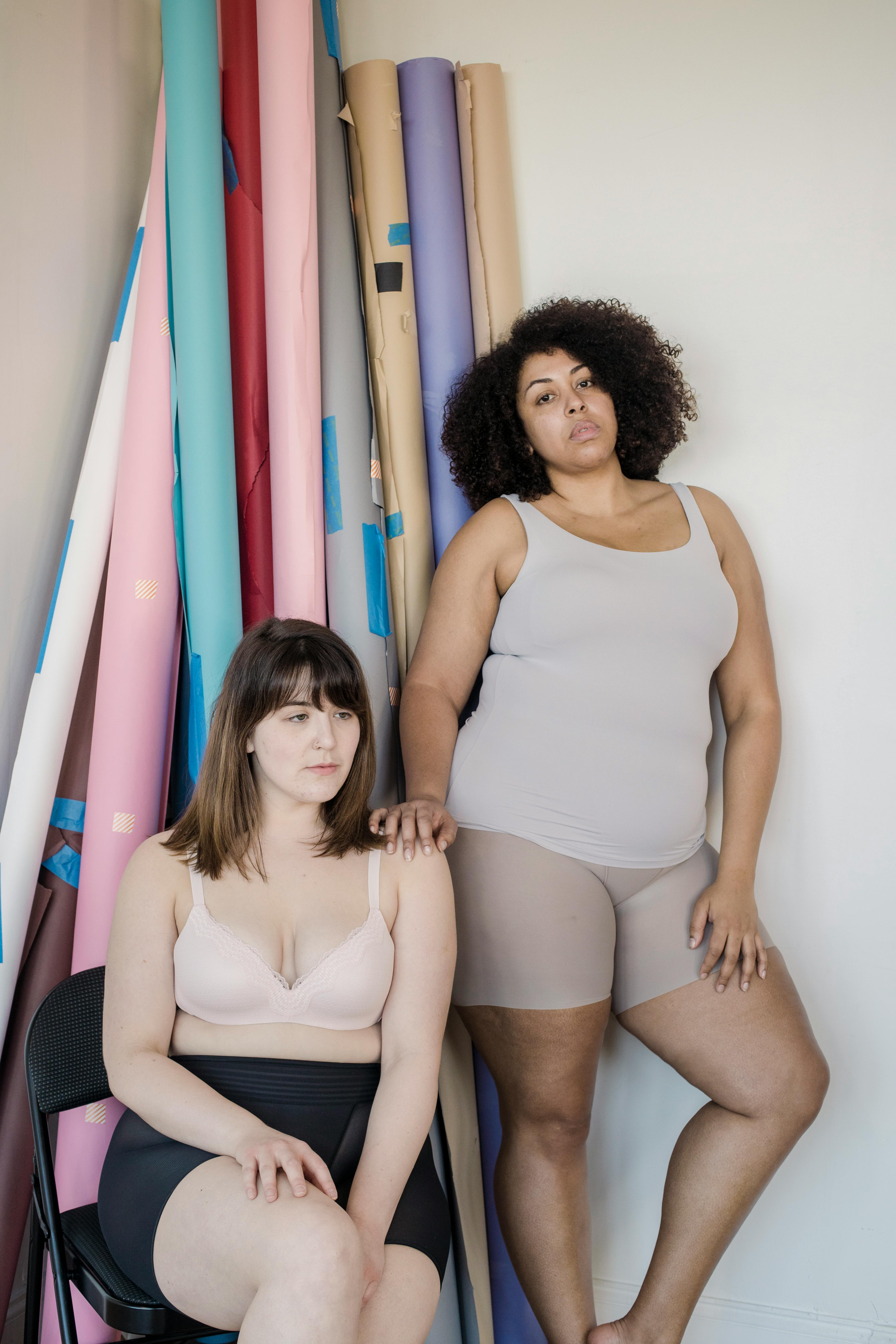 Overweight diverse girlfriends in underclothes against paper rolls