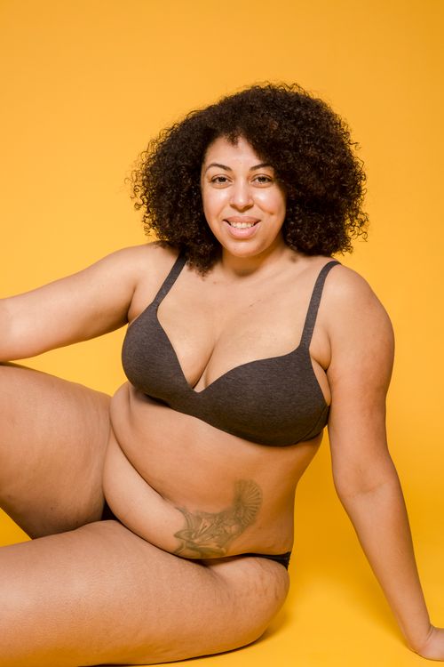 Free Cheerful overweight ethnic female in lingerie with Afro hairstyle looking at camera on yellow background Stock Photo
