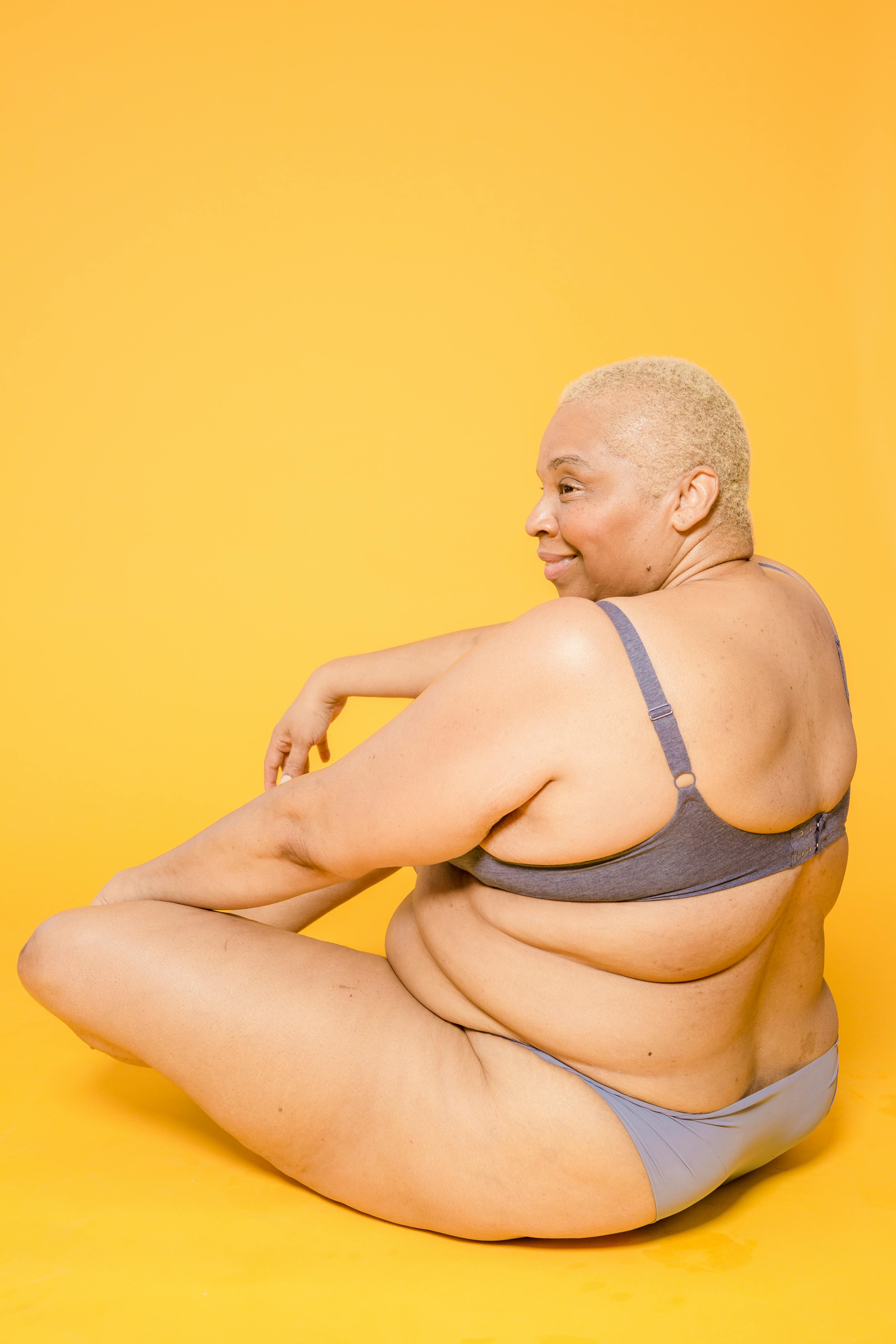 smiling overweight ethnic model in underwear on yellow background