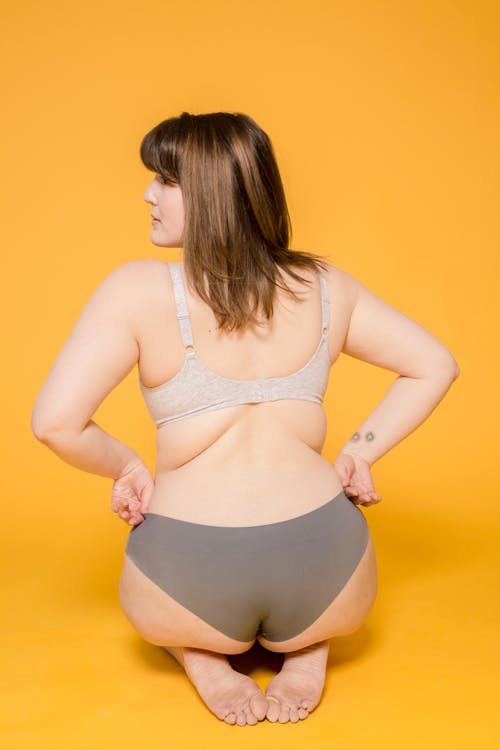 Free Woman in Underwear Sitting with Hands on Waist Stock Photo