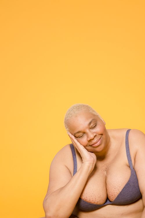 Free Mature woman with short hair posing peacefully against a vivid yellow background, conveying calm and relaxation. Stock Photo