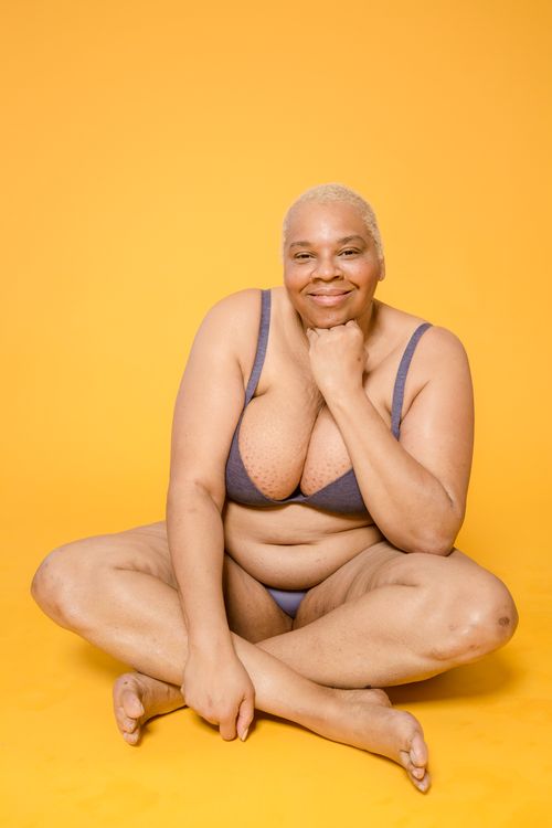 Free A joyful plus-size woman in lingerie sitting cross-legged, embracing self-love and body positivity. Stock Photo