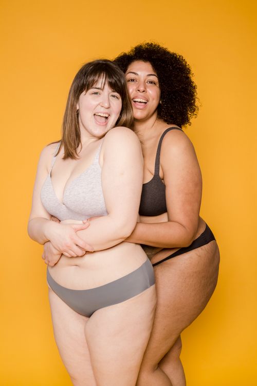Free Two women embracing, celebrating diversity and confidence against a vibrant yellow background. Stock Photo