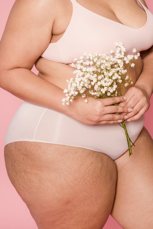 
A Close-Up Shot of a Woman in Her Underwear Holding Flowers