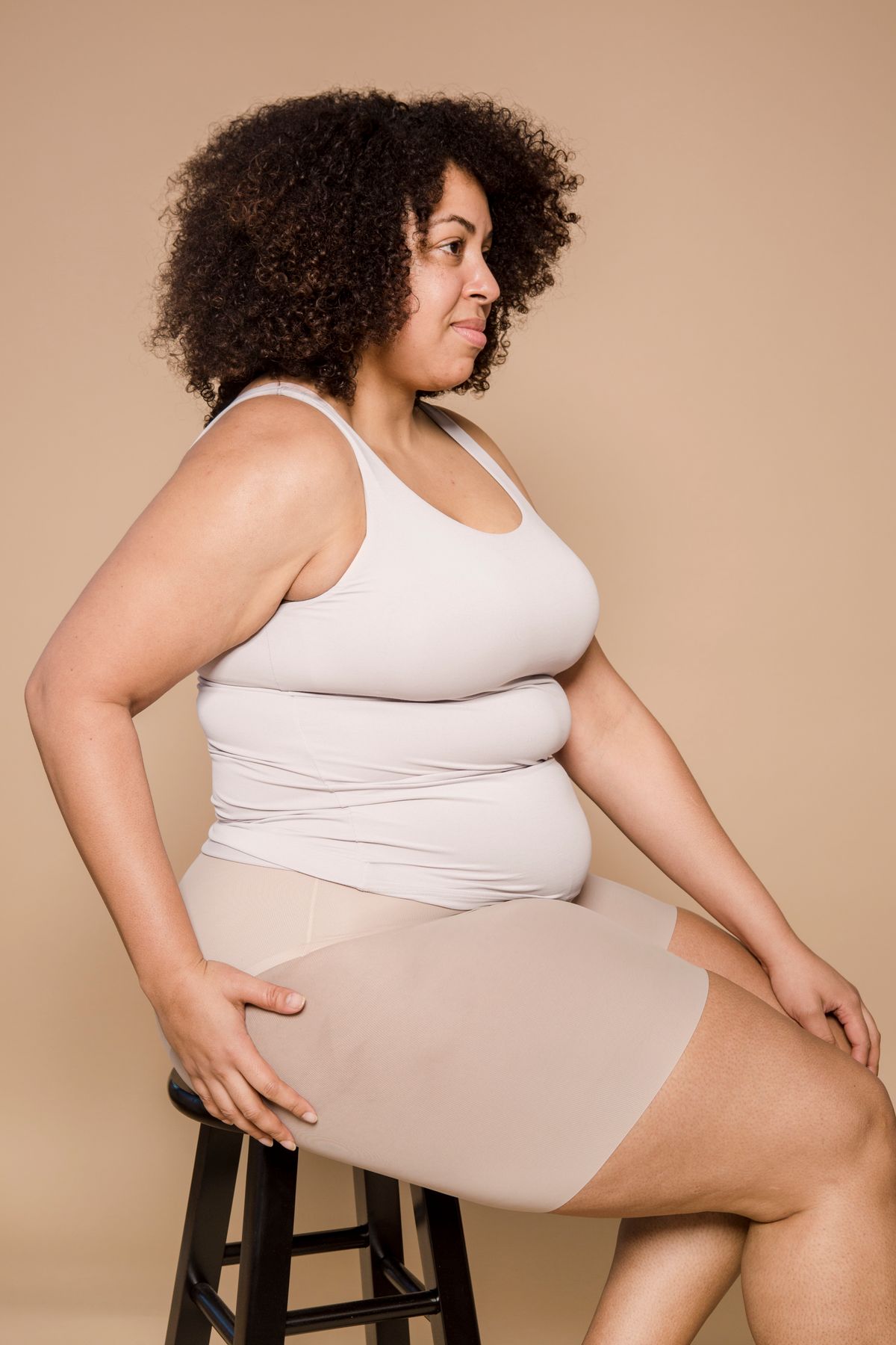 Smiling plus size woman seated comfortably in shaping underwear Smiling plus size woman seated comfortably in shaping underwear