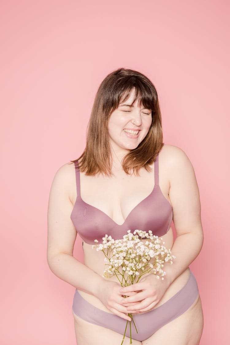 Joyful Overweight Asian Woman In Lingerie With Bouquet In Hands