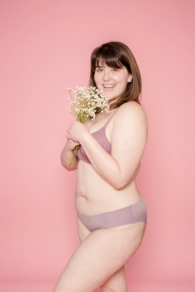 Happy Plump Asian Woman In Underwear With Flowers In Hands