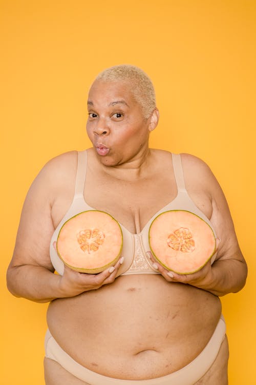 Cheerful plump black woman in underwear with melon in hands