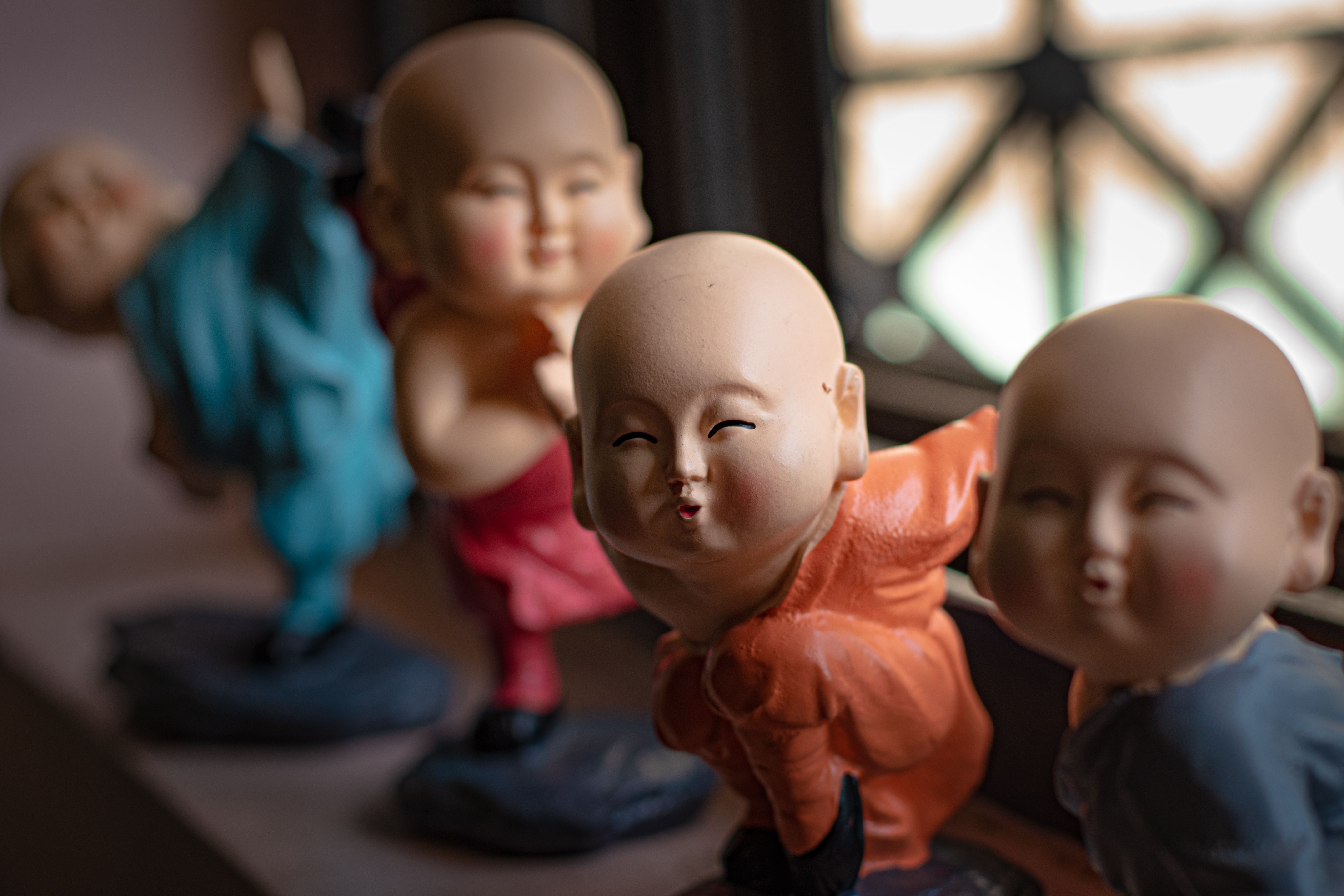 Close-up of colorful, cute monk figurines with expressive faces on display indoors.