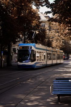 A modern tram traveling through a city street lined with trees, conveying urban transport.