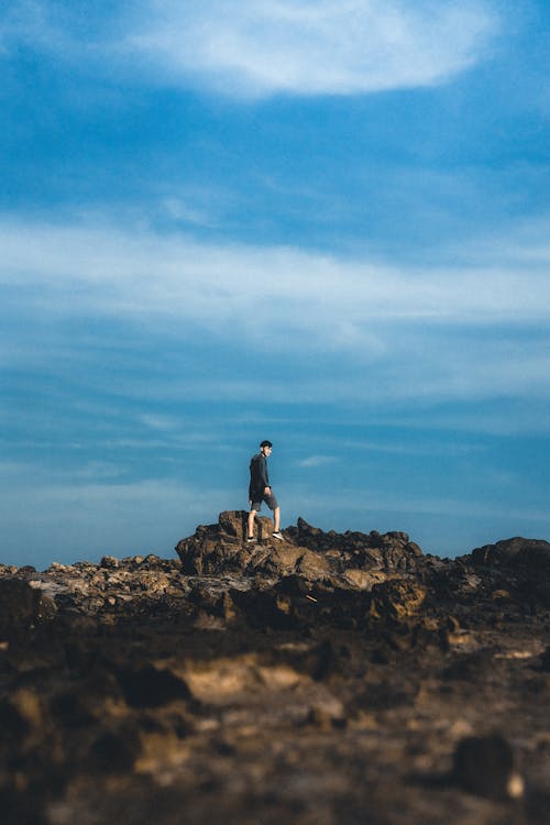 Free Man Standing on a Rocky Surface Under a Blue Sky Stock Photo