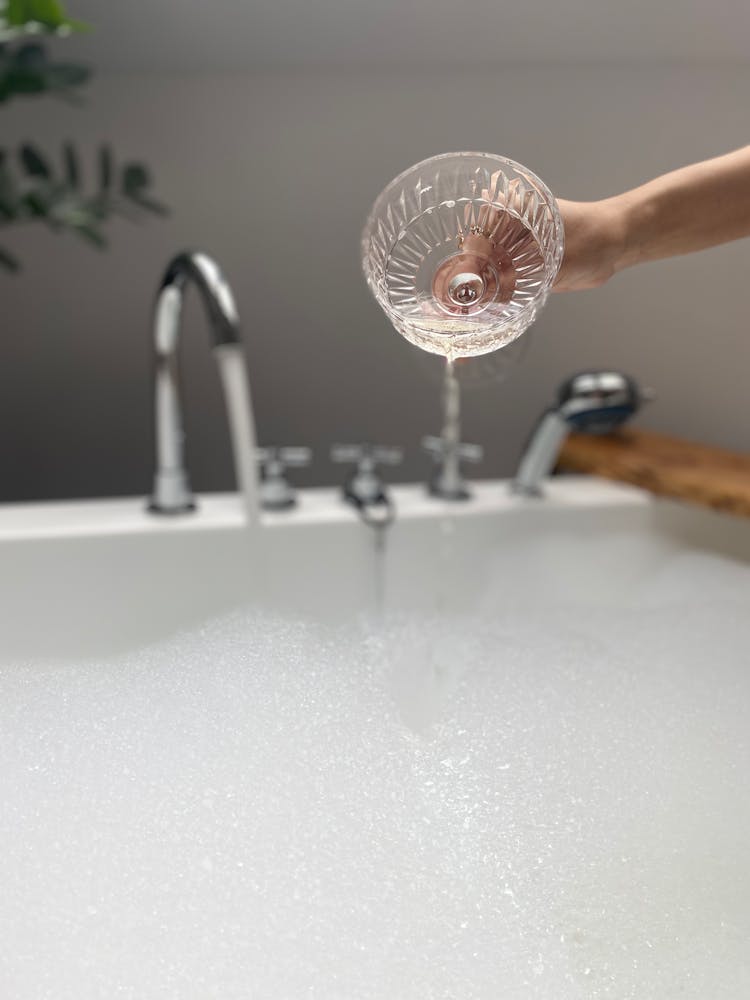 A Person Pouring Champagne Into A Bubble Bath