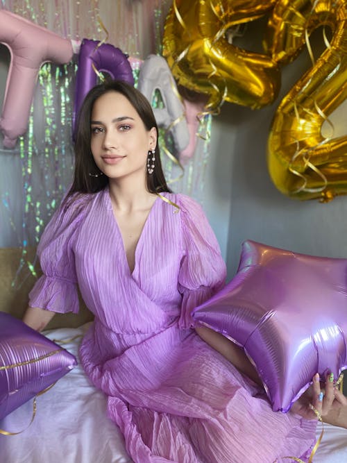 Free A Woman Wearing a Purple Dress and Holding Balloons Stock Photo