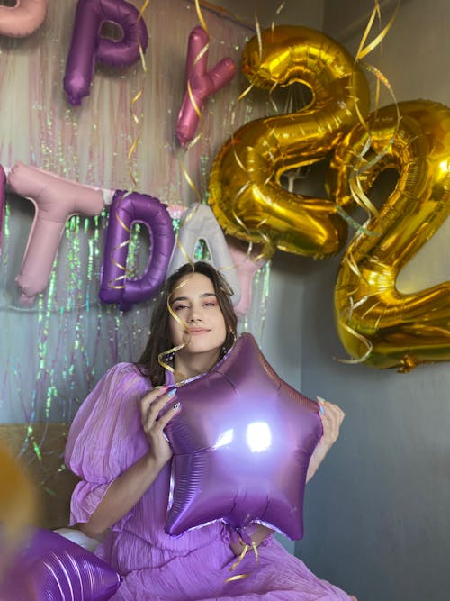 Free A Woman Wearing a Purple Dress and Holding a Balloon Stock Photo
