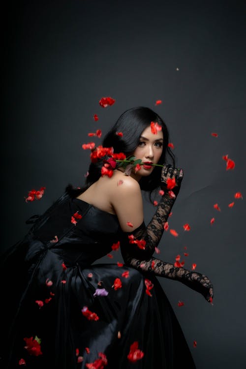 A Pretty Woman in Black Dress Holding a Red Flower