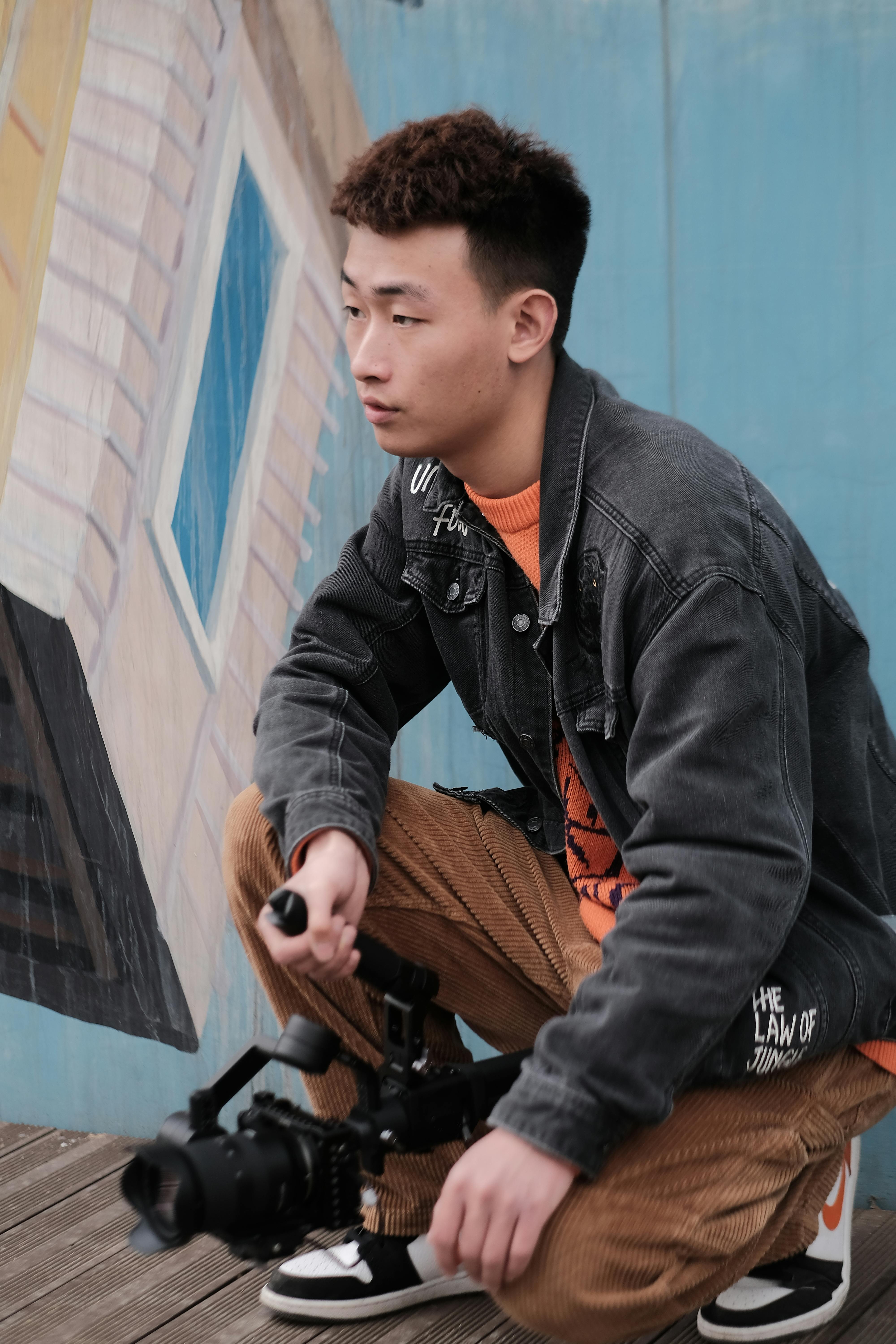 Young Asian male videographer holding a gimbal outdoors for shooting.
