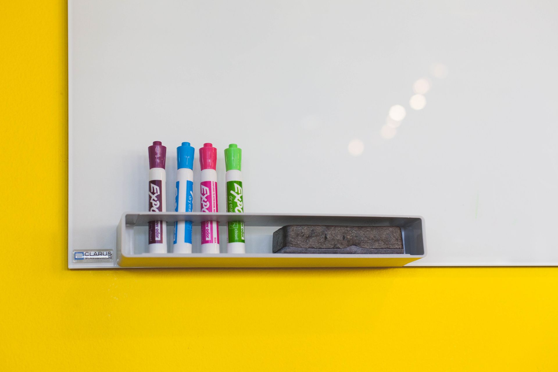 Colorful markers and eraser on a bright whiteboard in an office setting, ideal for brainstorming and planning.