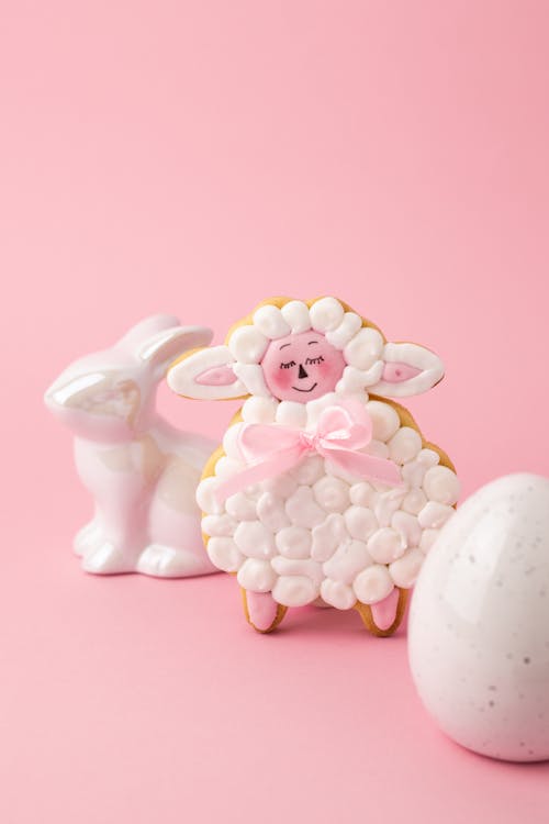 A Sheep Shaped Cookie Beside an Egg and a Ceramic Bunny Figurine