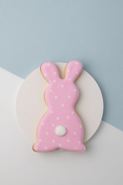 Free A pastel pink polka dot bunny cookie on a minimalist blue and white backdrop, perfect for Easter. Stock Photo
