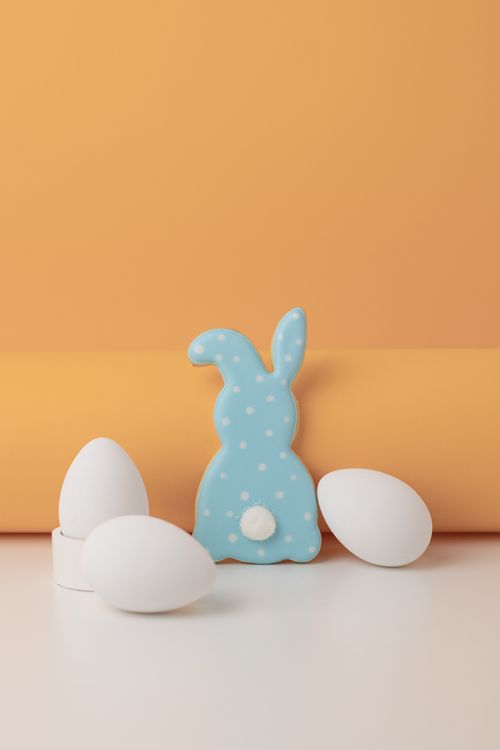 Free A cute polka dot bunny cookie with white eggs on an orange background, perfect for Easter celebrations. Stock Photo