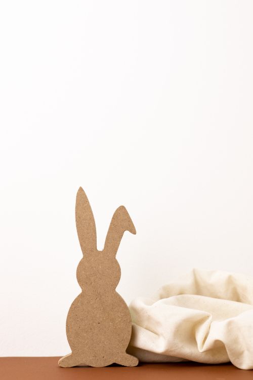 Free Simple Easter decor featuring a wooden bunny outline with soft neutral tones. Stock Photo