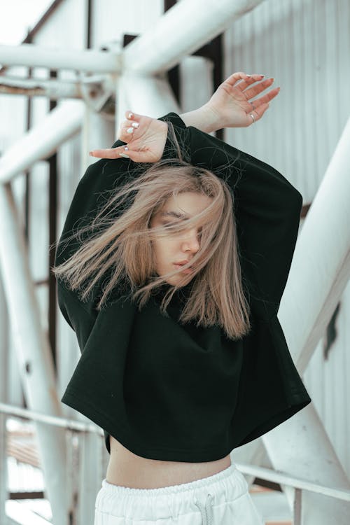 A Blonde Woman in Black Top Raising Arms