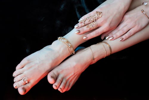 Crop unrecognizable woman legs and hands wearing oriental golden jewelry
