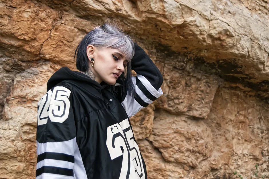 Femme portant un jersey oversize numéro 25 en style streetwear devant une paroi rocheuse