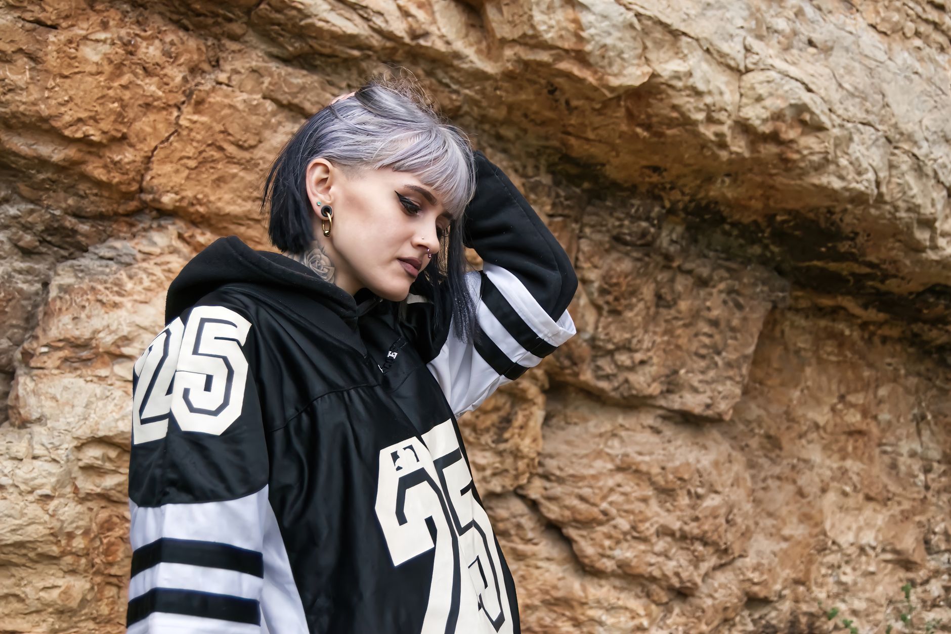 Femme portant un jersey oversize numéro 25 en style streetwear devant une paroi rocheuse