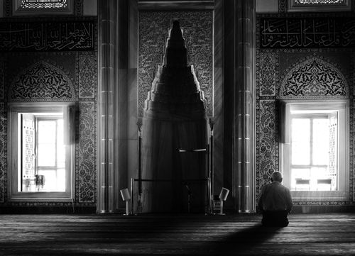 Free A man praying in a beautifully ornate mosque interior, captured in black and white. Stock Photo