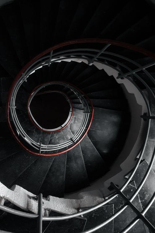 Free A stunning top-down shot of a spiral staircase with sleek black steps and metal railings. Stock Photo