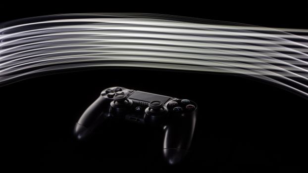 Close-up of a PS4 controller with dynamic light streaks on a black background.