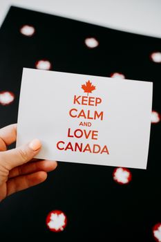 A card reading 'Keep Calm and Love Canada' held against a decorative backdrop, perfect for Canada Day celebrations.