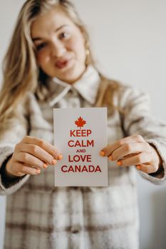 A woman holds a 'Keep Calm and Love Canada' card, celebrating national pride.