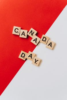 Scrabble tiles on red and white backdrop spell 'Canada Day,' symbolizing national pride.