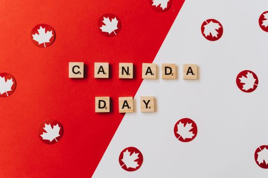 Image of Scrabble tiles spelling 'Canada Day' on a festive red and white background.