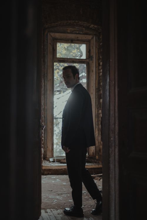 Free Side view full body of anonymous male in stylish outfit standing near doorway of spacious abandoned building with shabby walls Stock Photo