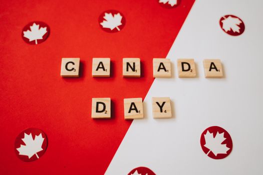 Canada Day themed image with scrabble pieces spelling 'Canada Day' and maple leaves on a red and white background.