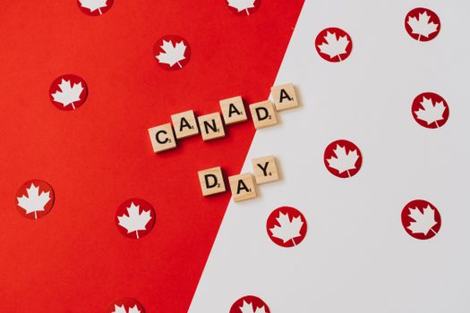 Canada Day themed illustration with Scrabble tiles and maple leaves on a red and white background.