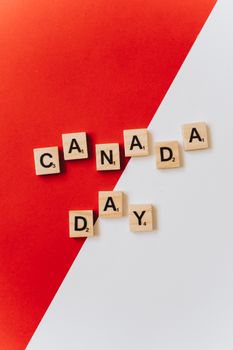 Scrabble tiles spelling 'Canada Day' on a red and white background, symbolizing celebration.